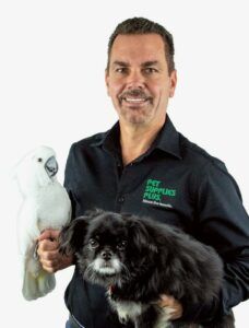 Photo of Chris Rowland, CEO of both Wag N Wash, Dog Grooming Franchise, and Pet Supplies Plus, smiling and holding a bird and a dog